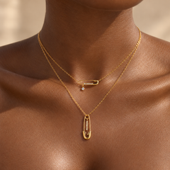 Collier BINTOU doré à deux rangs et motifs épingles à nourrice, porté sur peau foncée